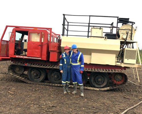 Two men standing in front of a red truck.